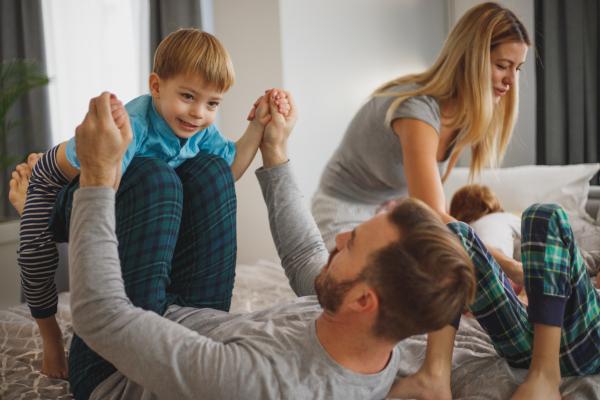 Two parents playing with the kids on a bed