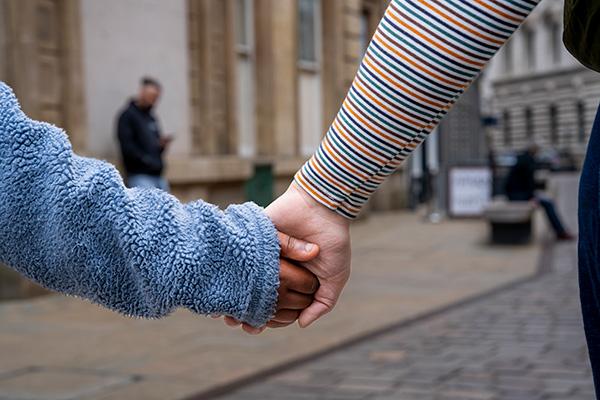 An adult and child holding hands