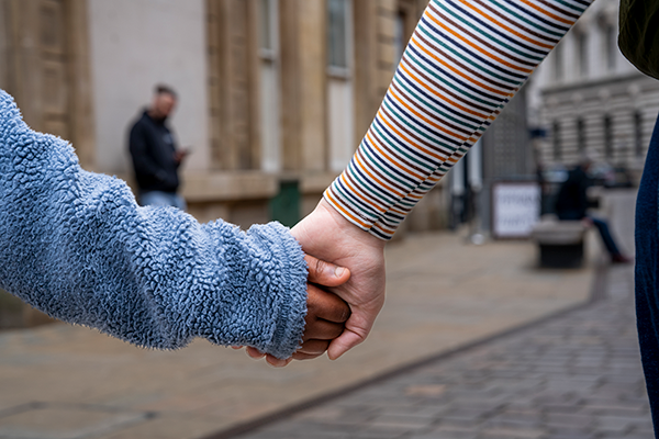 An adult and child holding hands