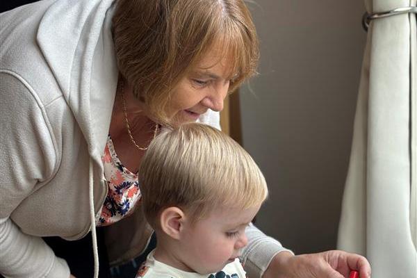 woman with blonde toddler playing at low table